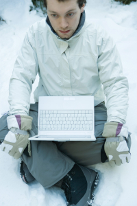Photo of man holding laptop in snow.